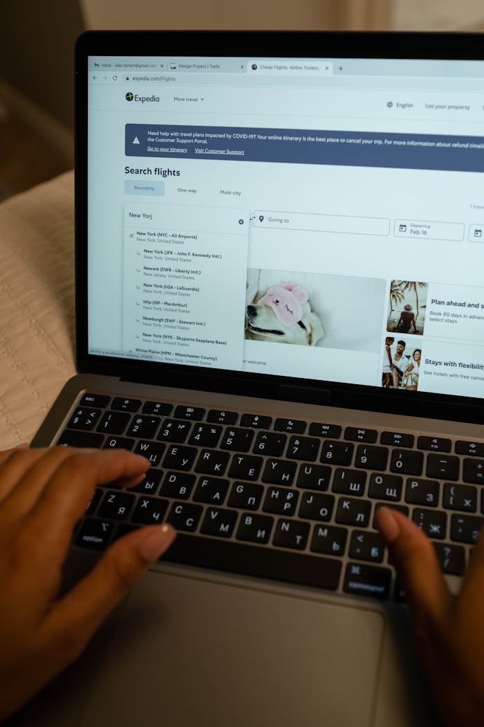 Home Person typing on laptop, searching flight details indoors, focusing on travel planning and booking.